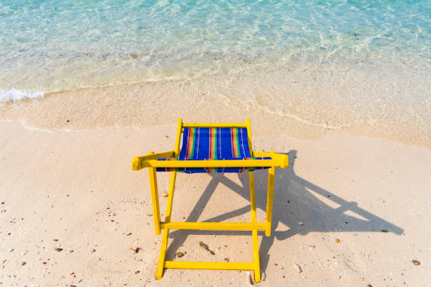 A single wooden chair on a Caribbean beach facing out towards the Caribbean Sea.