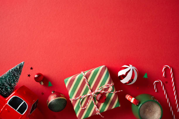 istock Christmas flat lay composition with a vintage gift box, truck with Christmas tree, balls, candy canes on red background 2181854501