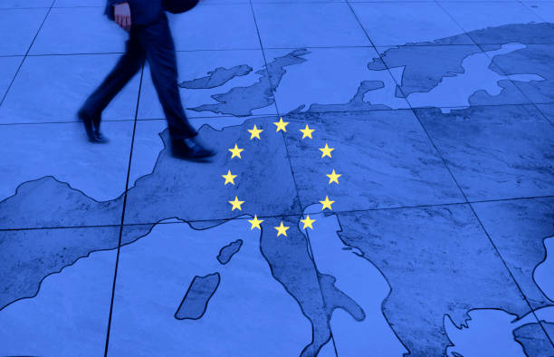Multiracial group of hands and arms of men and women clasping each other, signifying unity, solidarity, cooperation and teamwork, around the EU flag.