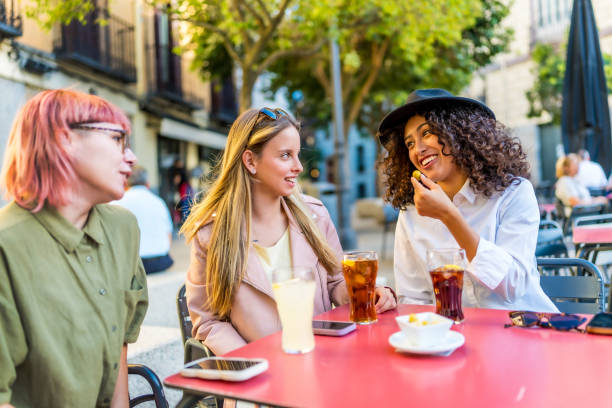 istock Modern women sitting on sidewalk bar drinking and eating snacks 2181859438