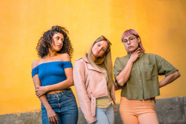 istock Three diverse beauty women standing against yellow urban wall 2181859552