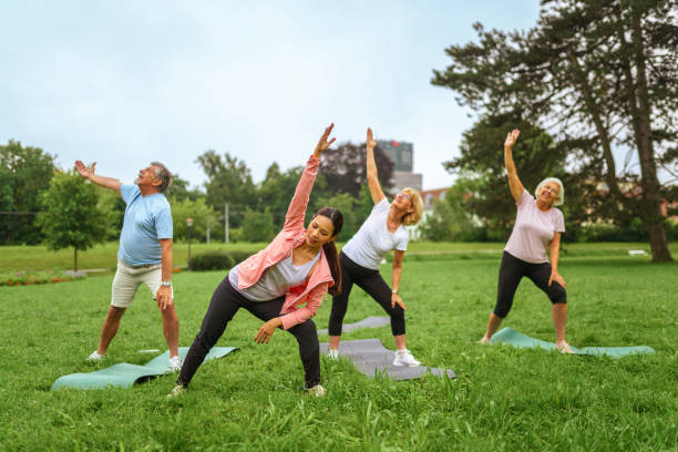 istock Senior Group Yoga Session with Instructor in Park 2181860079