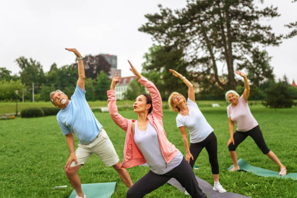 istock Senior Group Yoga Session with Instructor in Park 2181860083