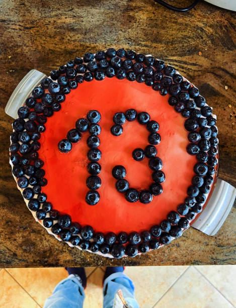 Birthday cake decorated with blueberries on top made for thirteenth birthday placed on a table