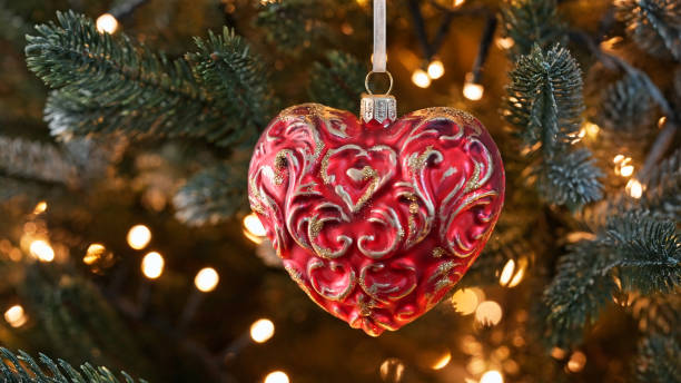 istock Christmas ornament red heart-shaped with golden decorative patterns close-up, hanging on Christmas tree. Warm lights illuminate festive scene, adding romantic cozy holiday feel. Winter family holiday 2181862834