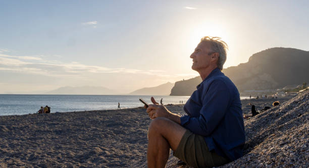 istock Mature man uses mobile phone on beach 2181863754