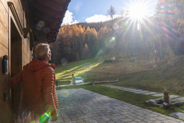 Mature man walks through chalet door onto patio at sunrise, Livigno