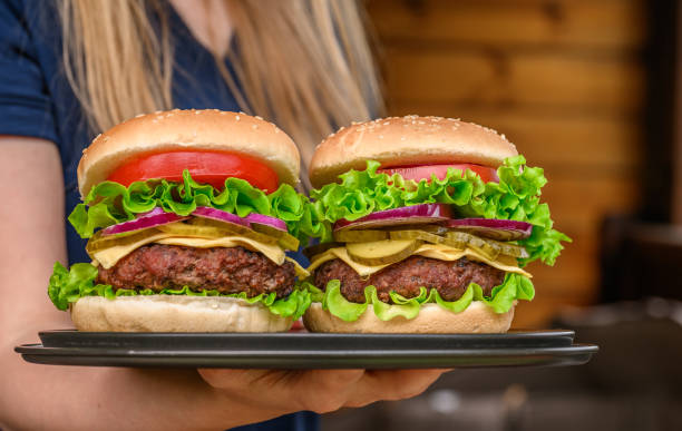Two beef cheeseburgers carried by a waitress on a tray