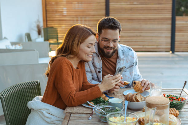 istock Couple enjoying breakfast together on a sunny morning and using smartphone 2181868268