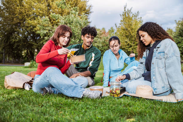 istock four young people having picnic in the park 2181870532