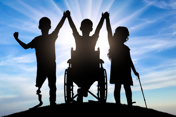istock Silhouettes of three children with different disabilities standing together holding hands 2181872318