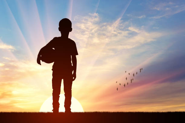 Sunset Silhouette of a Child with a Ball. Concept of childhood, dreams, and the beauty of growing up