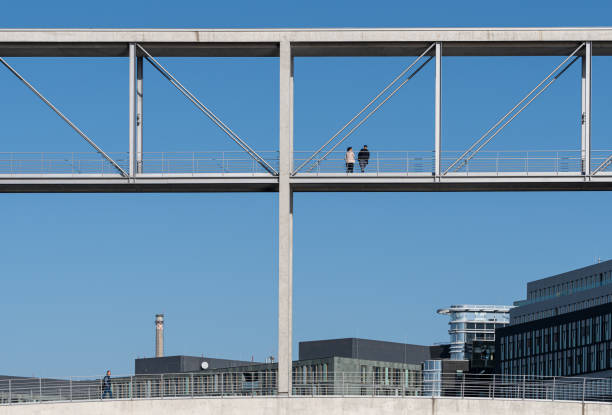 Germany, Berlin, Tiergarten,, Government district, October 17, 2024 - Rear view of two people standing on a modern pedestrian bridge