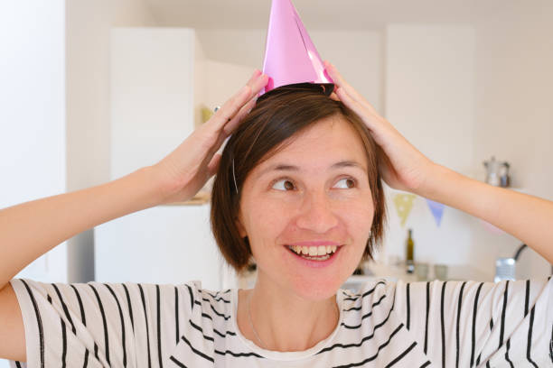 Asian woman celebrates her birthday at home, cozy atmosphere and festive decorations. She enjoys her special day with cake, candles, and warmth, creating memories in relaxed, joyful setting