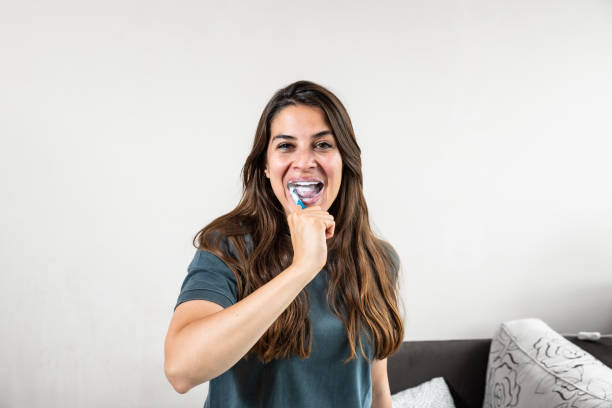 istock Smiling young woman brushing teeth in bathroom. Happy girl looking in mirror while using ecological toothbrush with whitening toothpaste. Beauty girl in bathroom cleaning teeth in the morning time. 2181878846