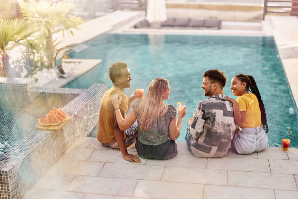 istock Back view of cheerful couples talking by the swimming pool. 2181880529