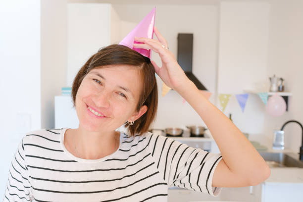 Asian woman celebrates her birthday at home, cozy atmosphere and festive decorations. She enjoys her special day with cake, candles, and warmth, creating memories in relaxed, joyful setting
