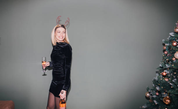 Photo of a smiling young woman by the Christmas tree.