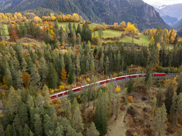 istock Red Train Journeying Through Autumn Forest in Mountain Valley 2181883218