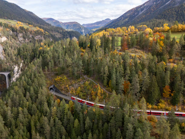 istock Red Train Journeying Through Autumn Forest in Mountain Valley 2181883273