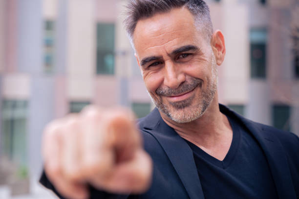 Confident middle adult pointing finger to front of logo. Smiling man pointing finger towards camera.