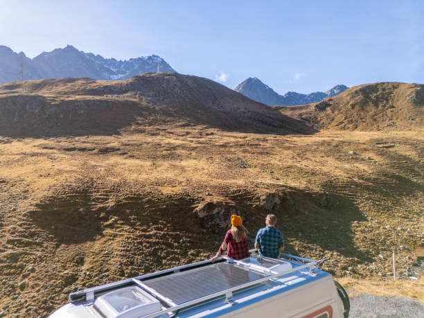 istock Couple Enjoying Mountain View from Camper Van Roof 2181888320