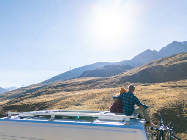 istock Couple Relaxing on Camper Van Roof Under the Sun 2181888321