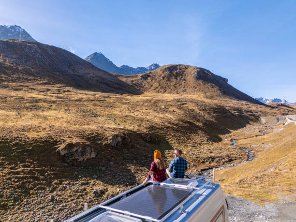 istock Couple Enjoying Mountain View from Camper Van Roof 2181888361