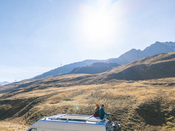 istock Couple Relaxing on Camper Van Roof Under the Sun 2181888362