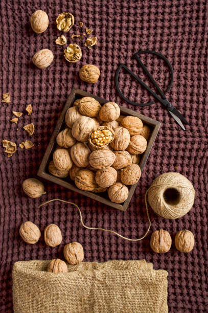 Walnuts in a square wooden box on a plum blanket