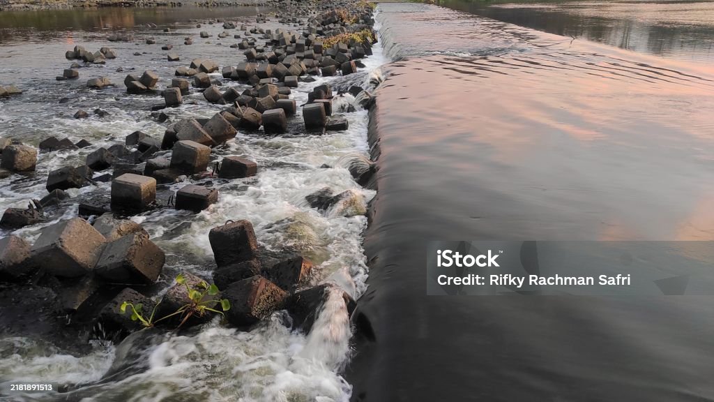 Large Angular Rocks River A River Cascades Over A Concrete Barrier Creating Textured Waves As It ...