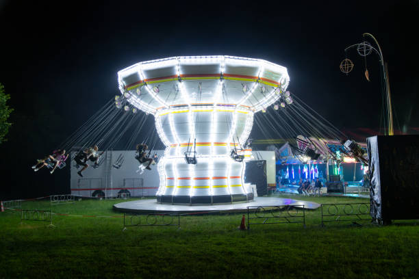Angera, Lombardei - Italy - 07-02-2024: A swing carousel in full motion, brightly illuminated at night, featuring passengers soaring through the air at a carnival in Angera, Italy.
