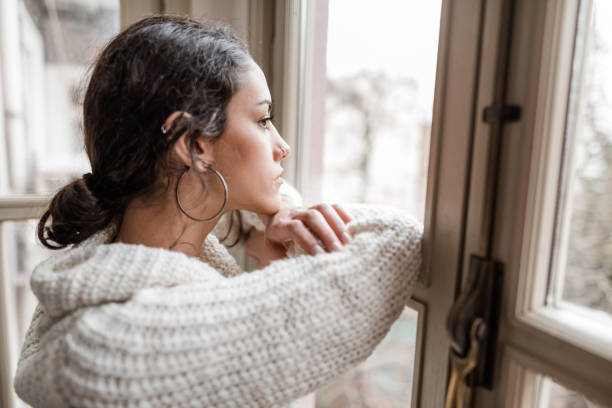 istock sad woman at the window 2181893613