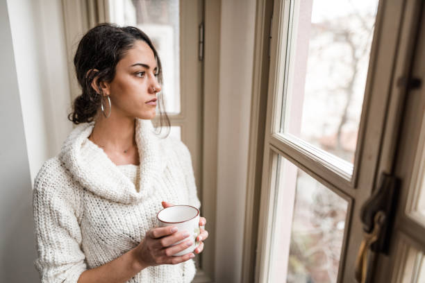 istock sad woman at the window 2181893695