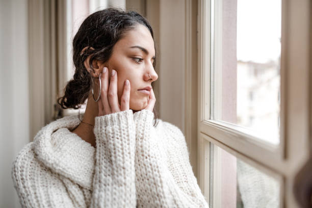 istock sad woman at the window 2181893730