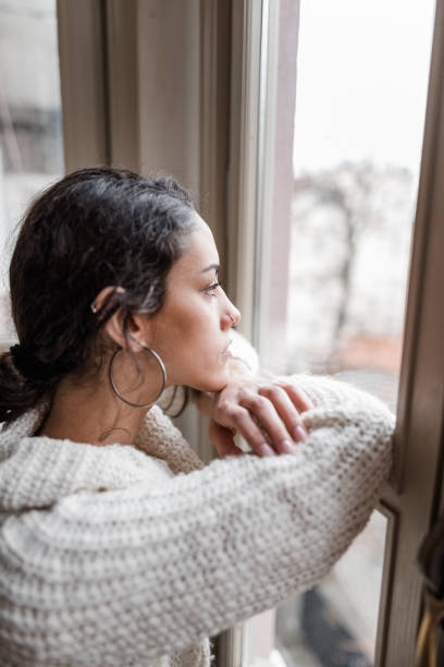 istock sad woman at the window 2181893767