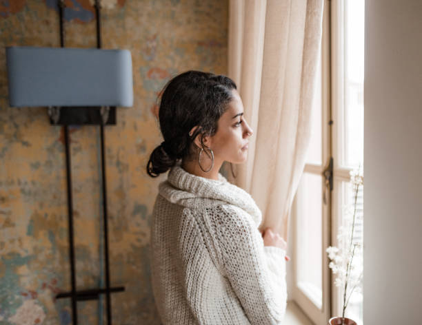 istock sad woman at the window 2181894048