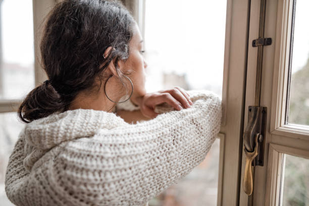 istock sad woman at the window 2181894158
