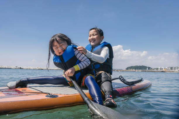 istock Asian siblings wearing life jacket playing  standup paddle boarding 2181894797