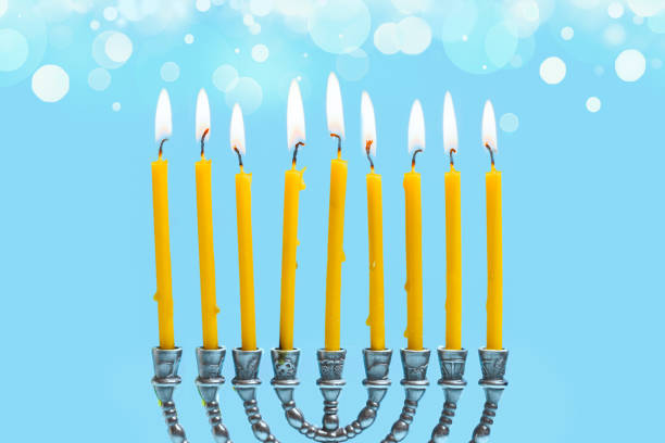 Hanukkiah, Hanukkah Menorah with nine burning candles on blue background with bokeh lights,  copy space.  Happy Hanukkah concept design. Traditional Hebrew Festival of Lights