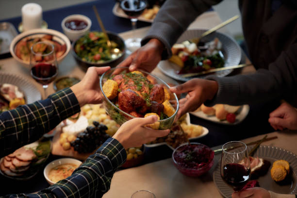 Man Passing Roasted Turkey at Dining Table while Eating at Christmas Dinner