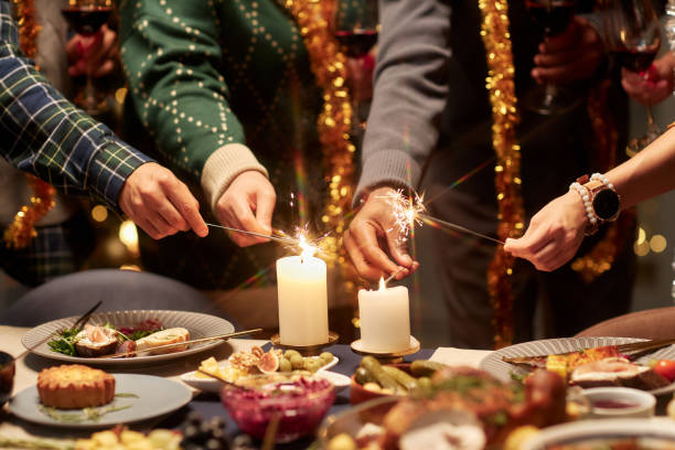 istock Hands of Multiethnic People Lighting Sparklers from Candlelight during Festive Dinner 2181900400