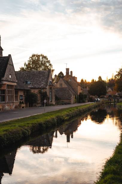 istock Cotswolds village at sunset with canal reflections. 2181901621