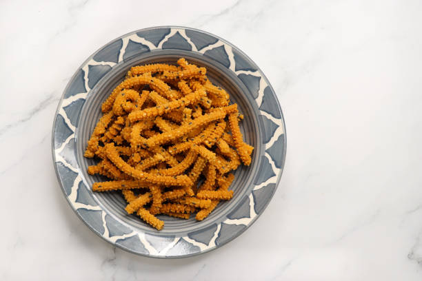 Crunchy fried homemade Chakli sticks with sesame seeds. Chakli is a savory snack from India made out of rice, mixed yellow and green lentils along with spices. Mostly eaten during Diwali festival palitos crujientes de chakli caseros fritos con semillas de sésamo. chakli es un sabroso bocadillo de la india hecho de arroz, lentejas amarillas y verdes mezcladas junto con especias. se come principalmente durante el festival de diwali