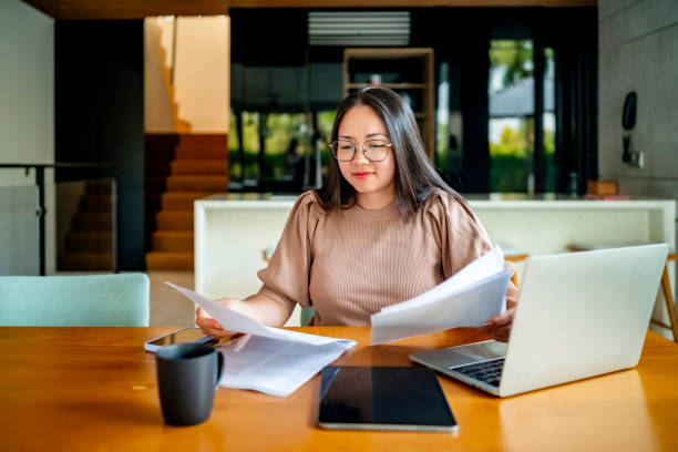 Young Woman Analyzing Documents at Home Office Desk