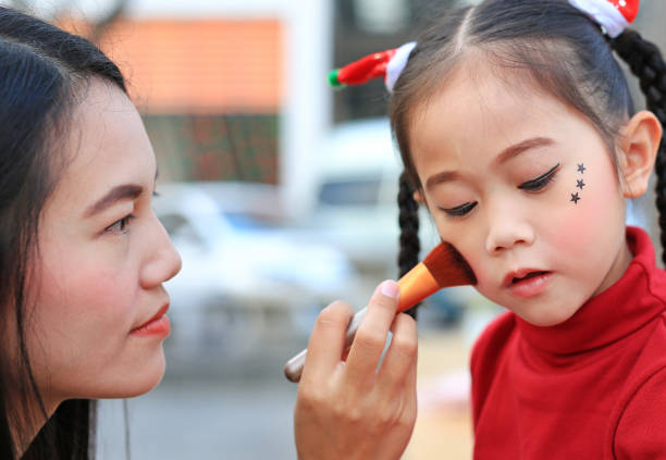 Close up Asian mother applying makeup on her daughter face.