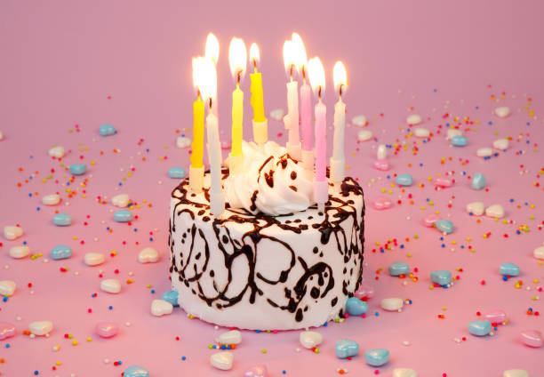 istock Birthday cake with burning candles on pink background 2181910013