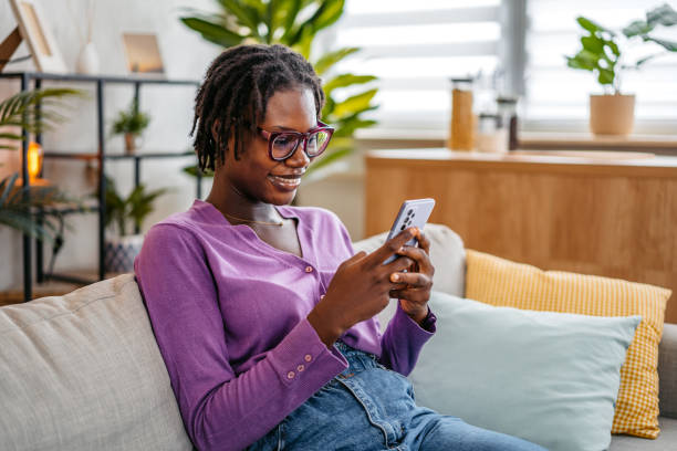 istock Young Woman Texting On The Phone While Sitting On The Sofa At Home 2181915822