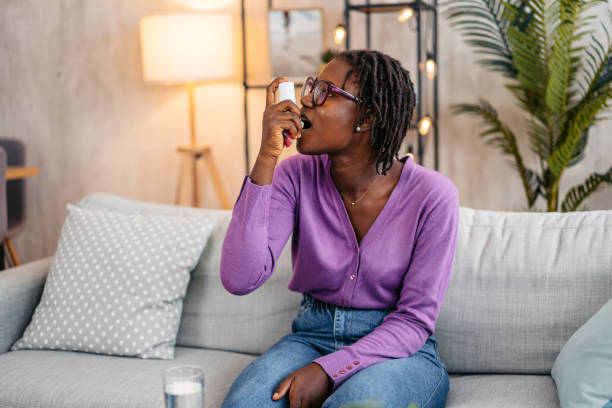 istock Young Woman Taking Asthma Inhaler While Sitting On The Sofa At Home 2181915922