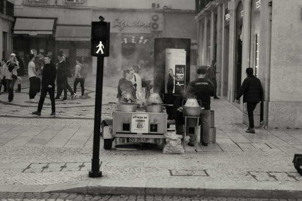 Lisbon, Portugal - November 11, 2023: Traditional roasted chestnuts vendors wait for clints at the Rossio Square in Lisbon downtown.